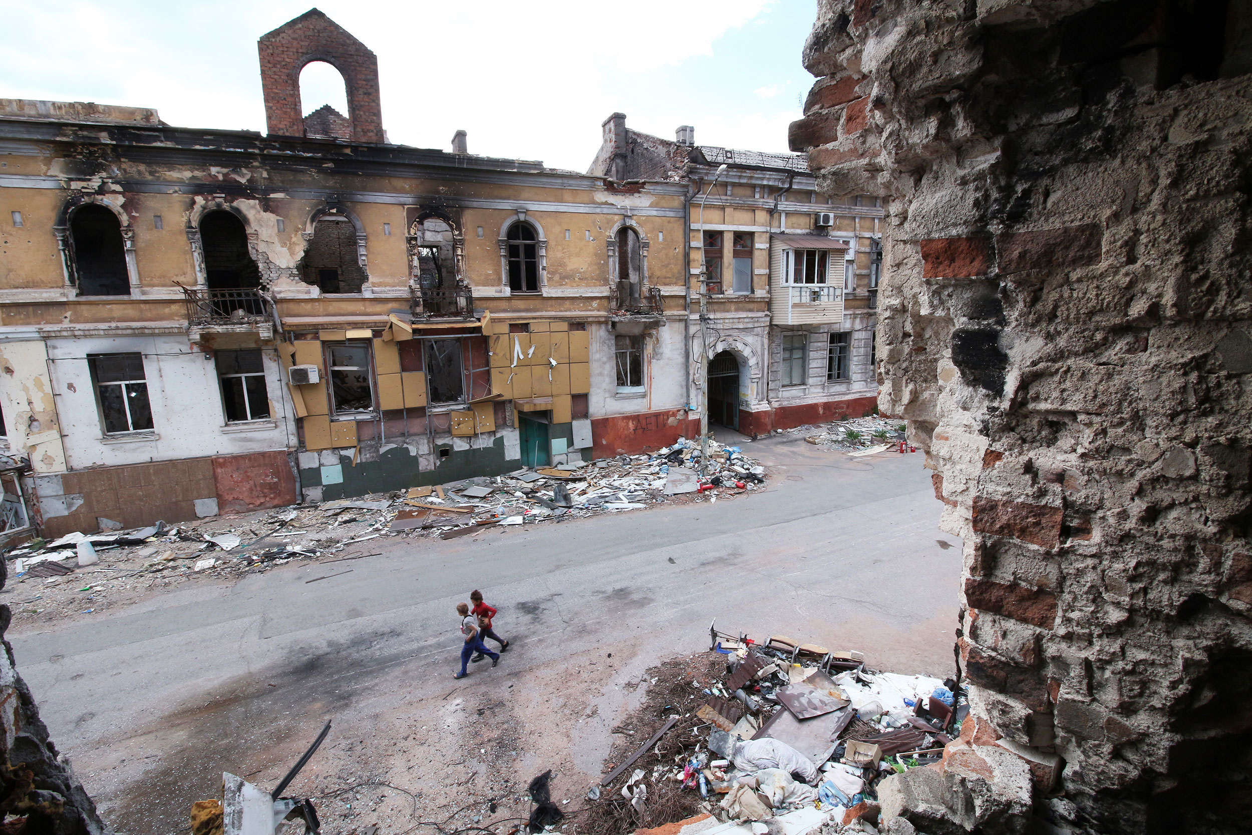 Children walk among buildings destroyed during fighting in Mariupol, in territory under the government of the Donetsk People's Republic, eastern Ukraine, Wednesday, May 25, 2022.