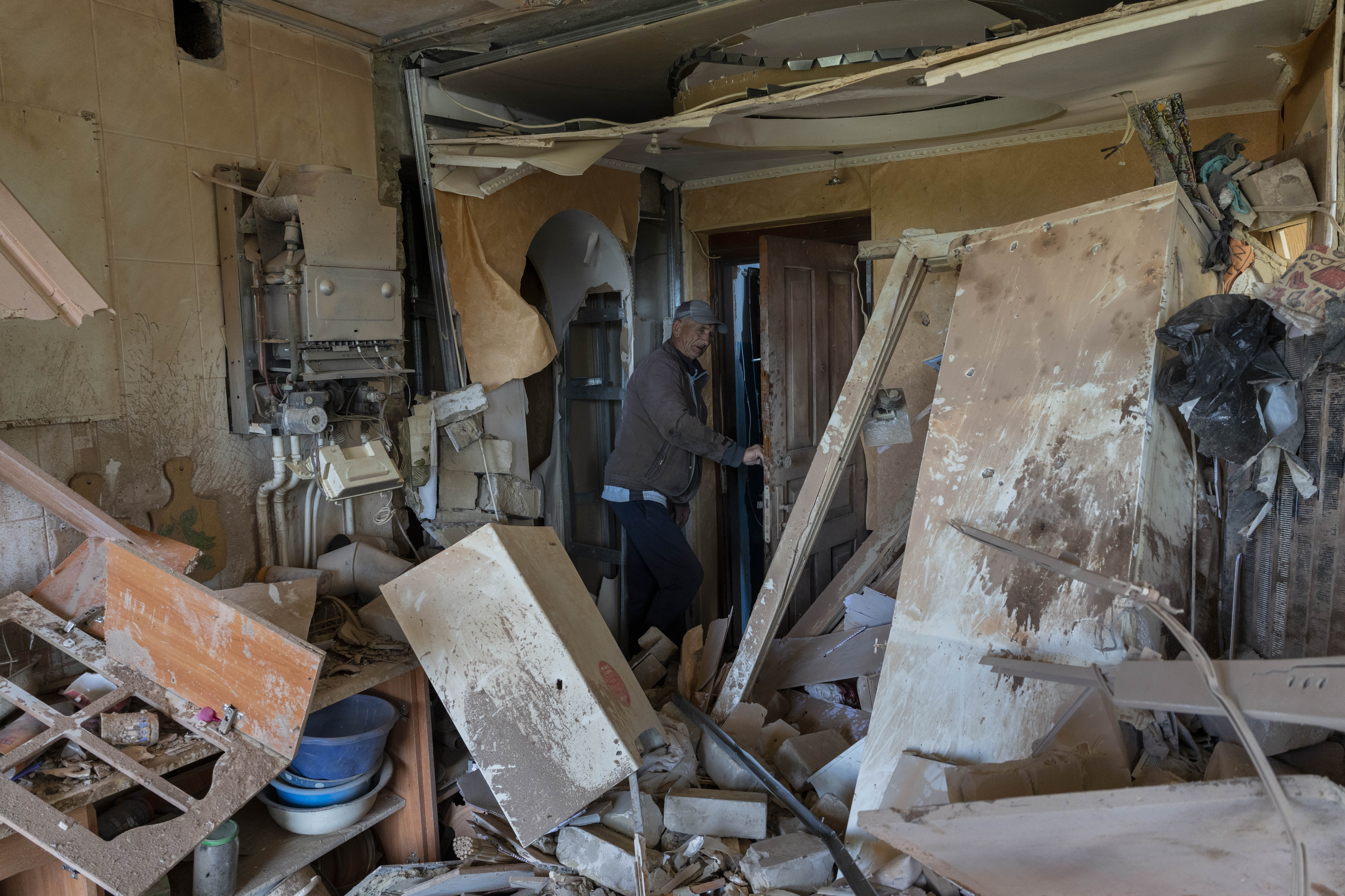 Resident Alexander, 67, checks the flat of his neighbour destroyed by shelling in Kutuzivka, near Kharkiv, eastern Ukraine, Friday, May 27, 2022. (AP Photo/Bernat Armangue)